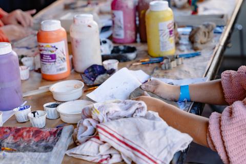 child's hands surrounded by paint and art tools