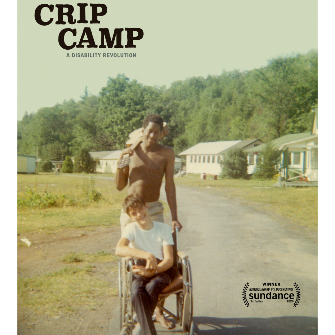 Crip Camp Film Poster. Man with guitar pushes person in a wheelchair in a forested camp setting.