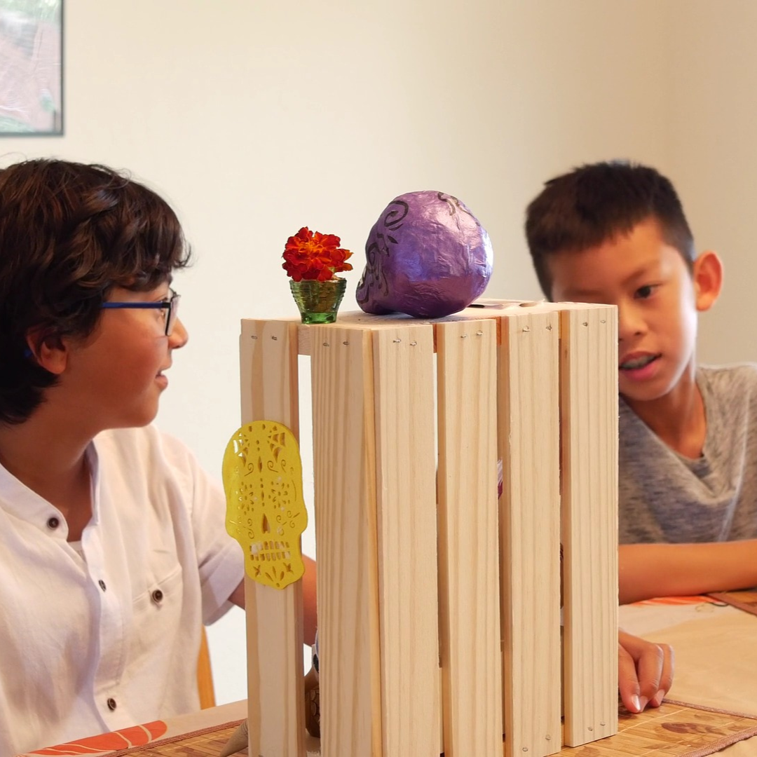 Screenshot from Terry Ngo's film "Ofrenda", image of two children creating altars for Dia de Muertos/Day of the Dead 